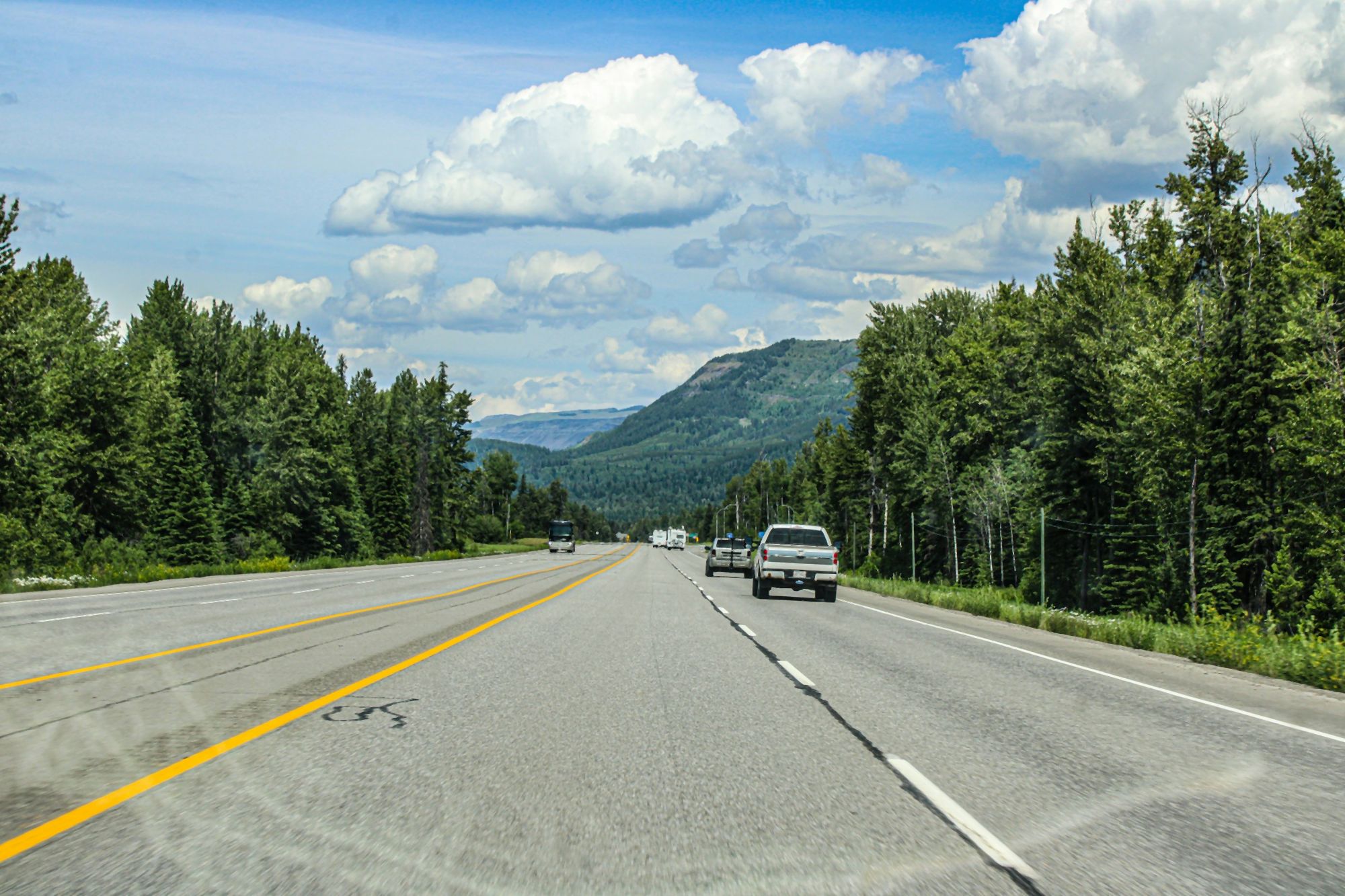 Highway through forested hills toward a mountain